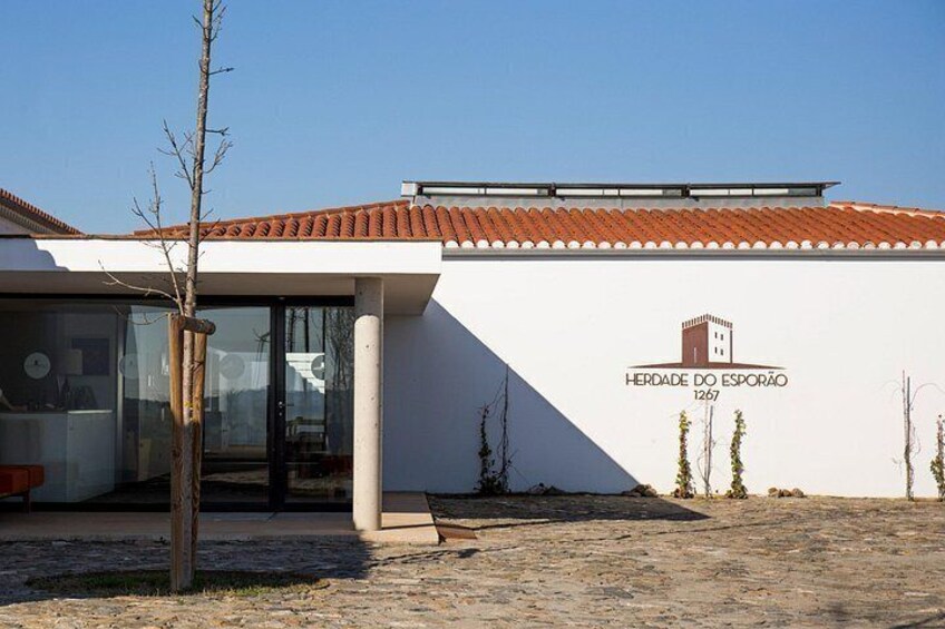 A building with a tiled roof and a sign that reads 'HERDADE DO ESPORÃO 1257'. 2