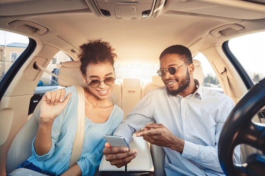 Two people sitting in a car, one holding a smartphone and the other pointing at it. 3