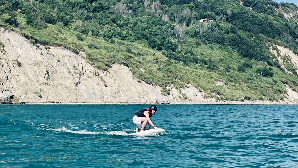 A person surfing on a wave in the ocean with a coastal landscape in the background. 3