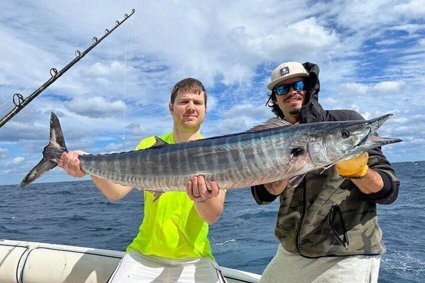 Two people holding a large fish on a boat in the ocean. 4