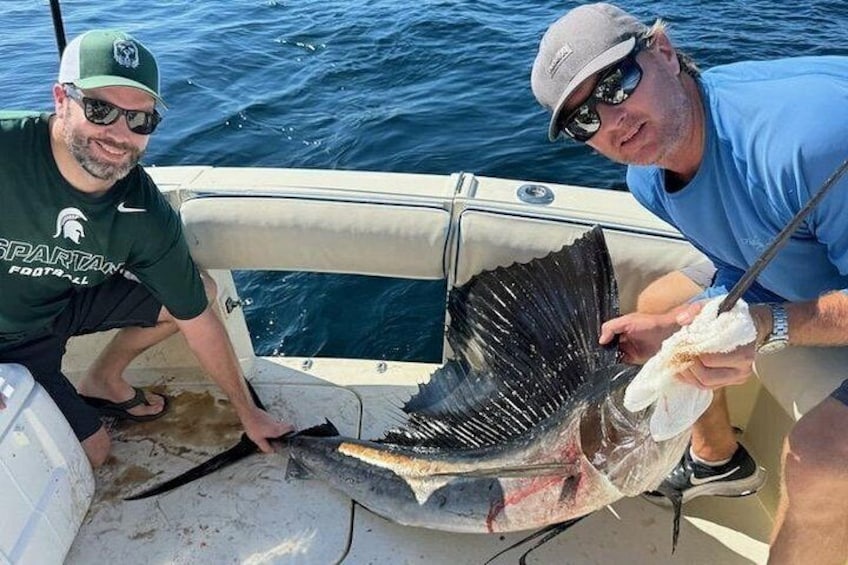 Two people on a boat holding a large fish. 3