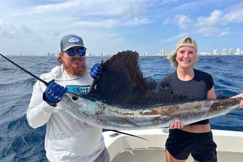 Two people holding a large fish on a boat with a city skyline in the background. 2