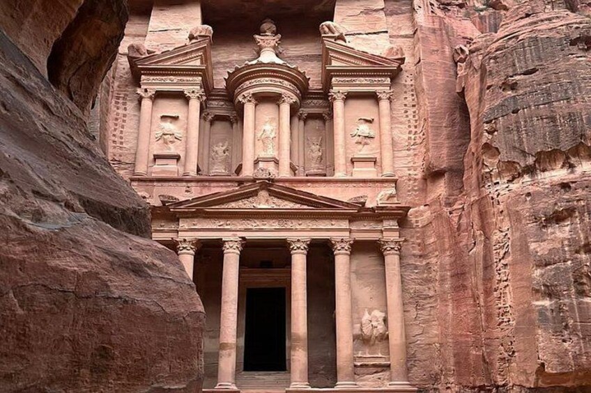 A carved rock facade with columns and statues, likely part of an ancient structure. 2