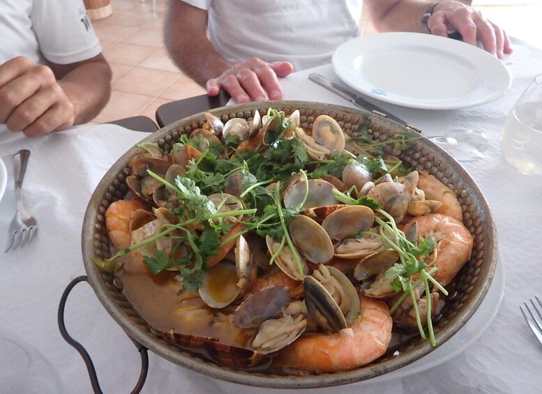A seafood dish with clams, shrimp, and herbs on a plate. 1