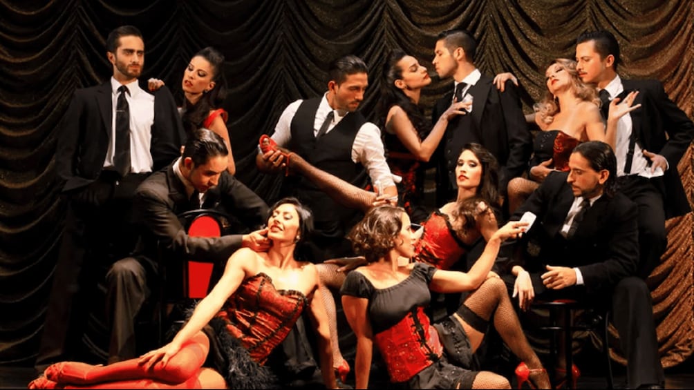A group of people in formal attire on a stage with a dark curtain backdrop. 4