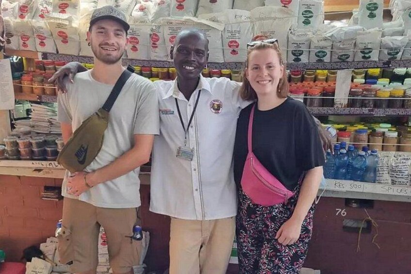 Tres personas de pie en una tienda con estantes llenos de diversos productos. 4