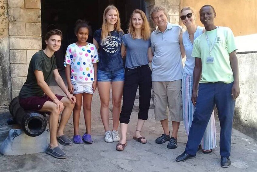 Un grupo de personas está de pie al aire libre frente a un edificio con un muro de piedra. 1