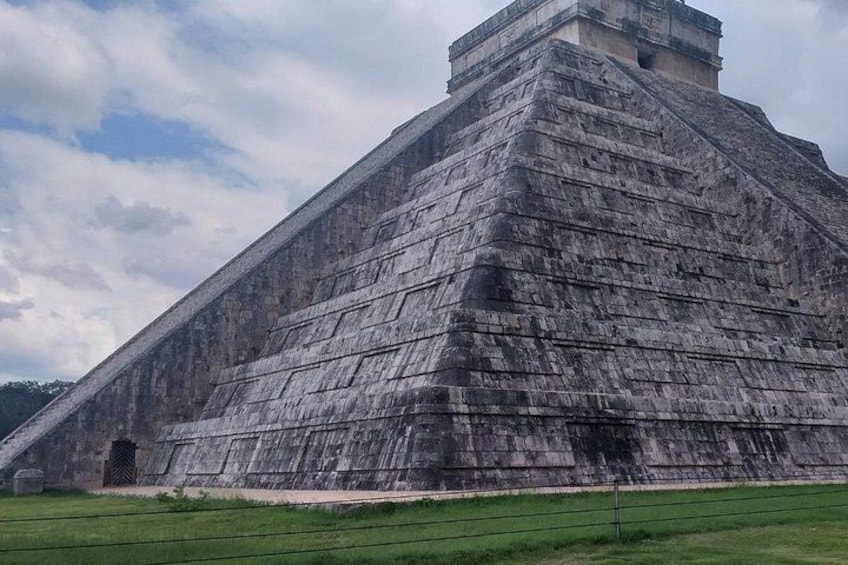 A large pyramid structure with a flat top and a smaller pyramid on top, surrounded by a grassy area. 4