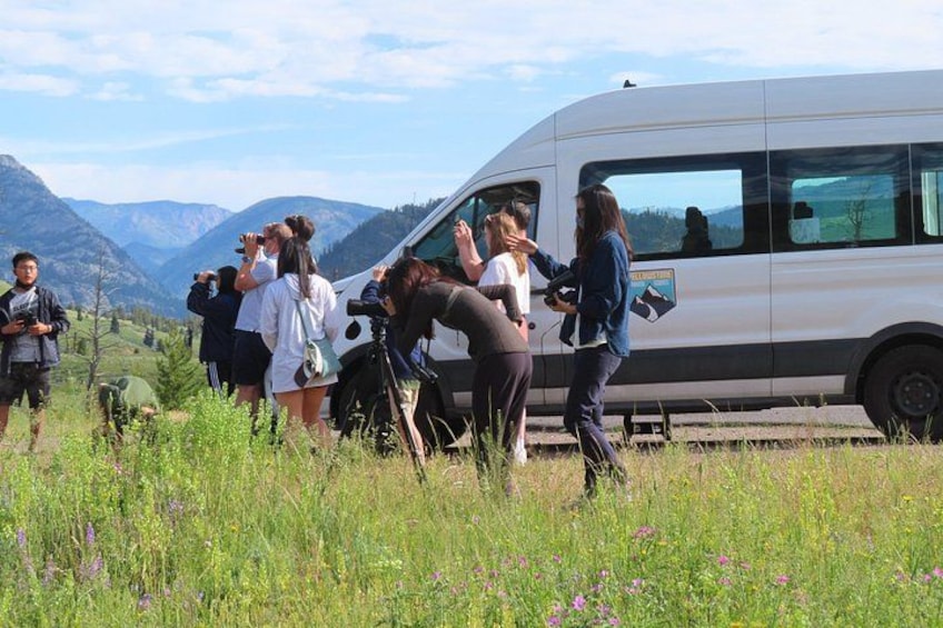 Un grupo de personas cerca de una furgoneta blanca en un campo con montañas al fondo. 1
