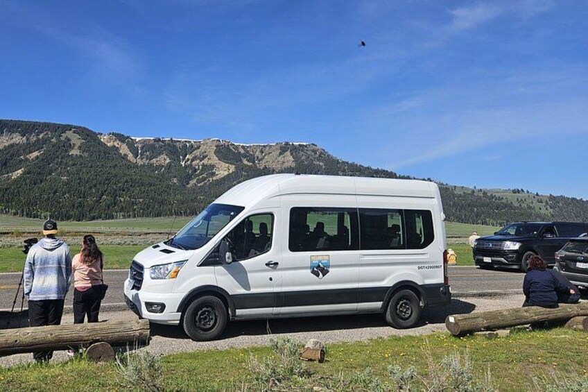 Una camioneta blanca estacionada en un camino de grava con montañas al fondo. 5