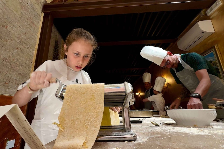 A person rolling dough on a table in a kitchen. 2