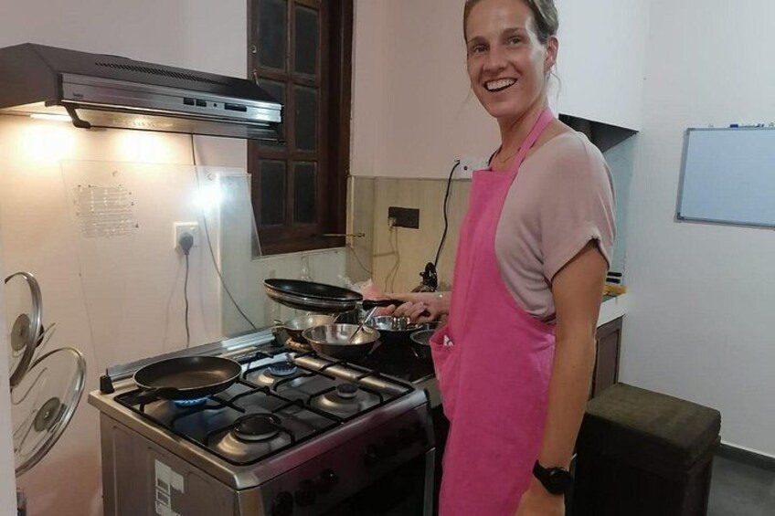 A person cooking in a kitchen with a gas stove, a frying pan, and a pot. 5