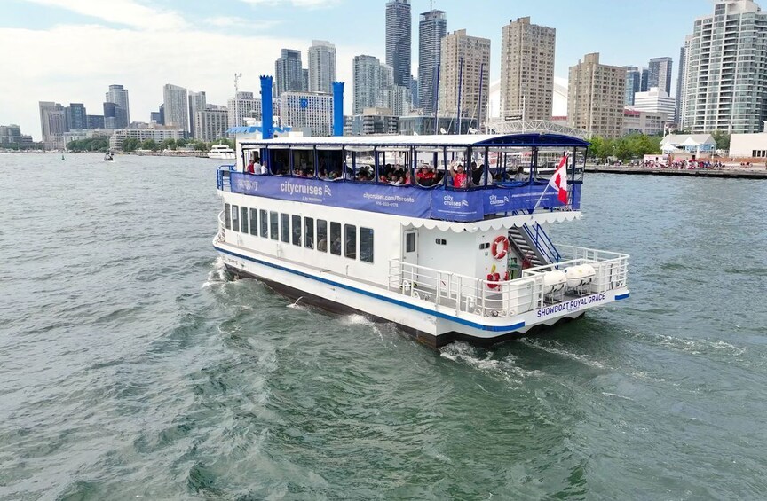 Een stadsrondvaartboot met 'citycruises' branding, die een rivier afvaart met een stadsachtergrond. 2