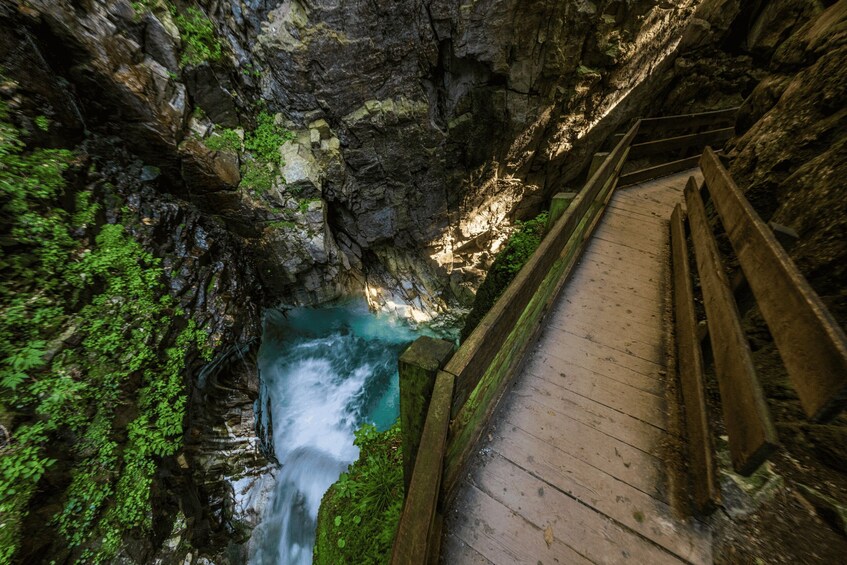 A wooden boardwalk beside a flowing river in a rocky gorge. 5