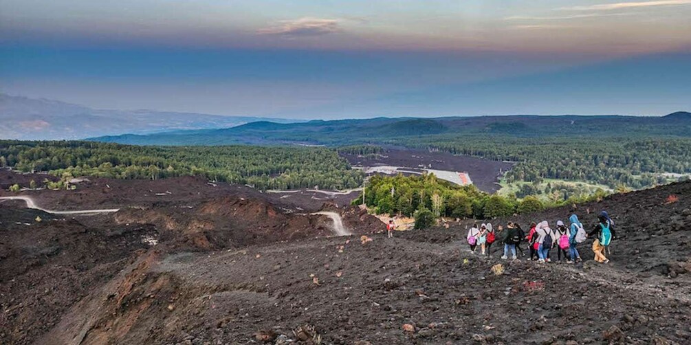 A volcanic landscape with a group of hikers on a trail. 1
