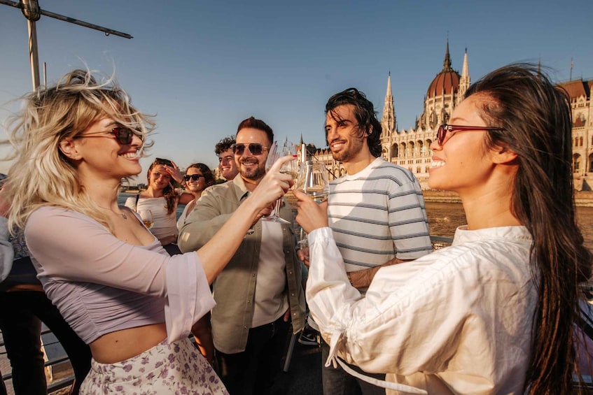 A group of people toasting with wine glasses in front of a historic building. 1