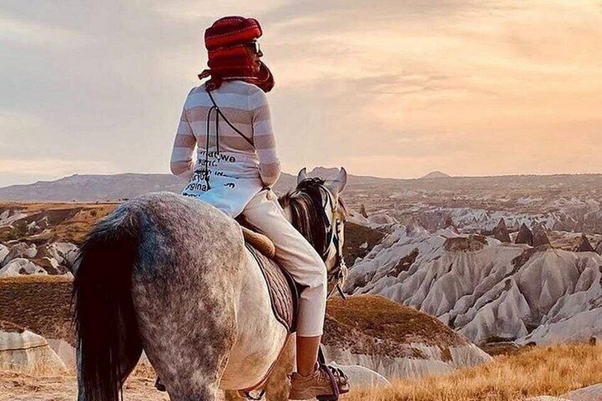 Una persona monta a caballo sobre terreno rocoso, con un extenso paisaje al fondo. 5