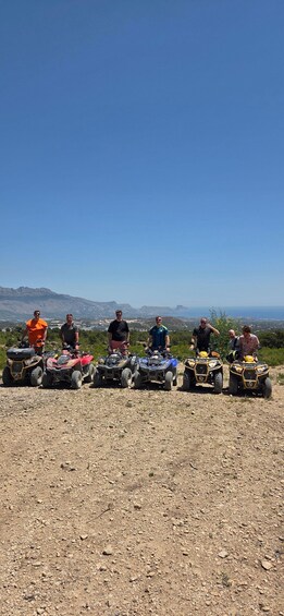 A group of people on ATVs on a rocky terrain with a clear sky and distant mountains. 5