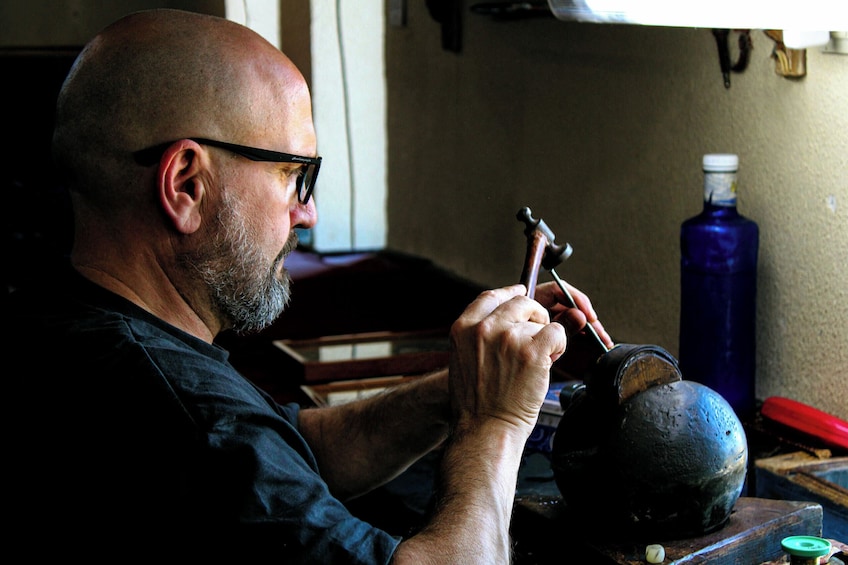A man working with a hammer and a metal object. 4