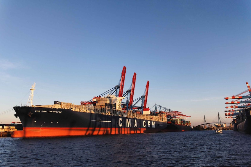 Een groot vrachtschip met kranen en containers afgemeerd in een haven. 5