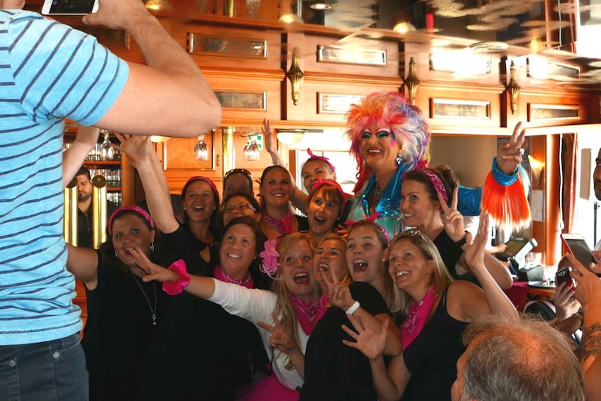 Een groep mensen in een bar met houten inrichting en hangende lampen. 4