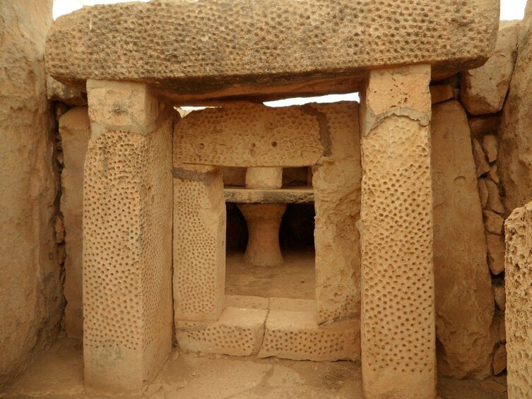 An ancient stone structure with a central stone platform and surrounding columns. 5