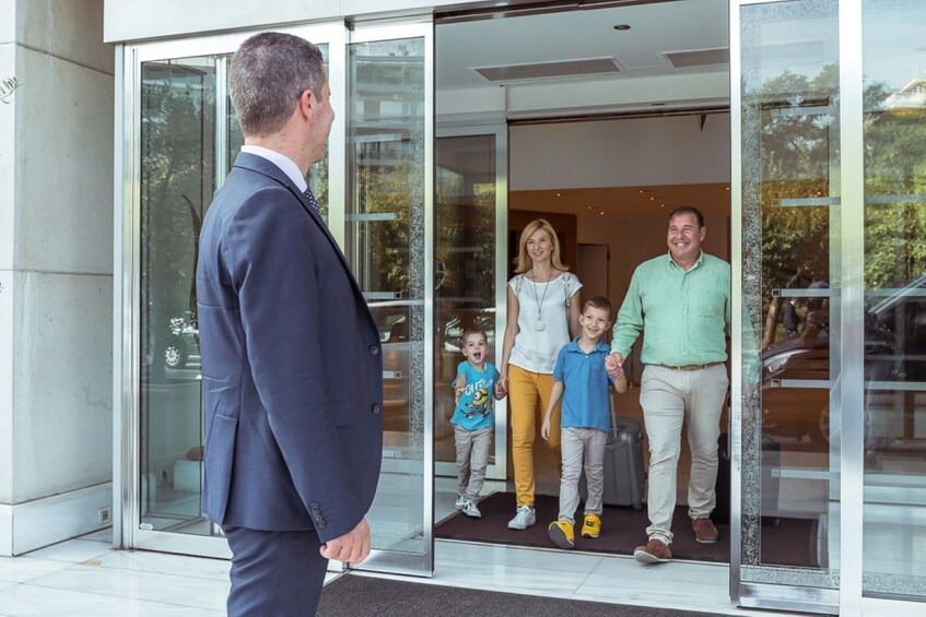 A family of four entering a modern building through a glass door. 2