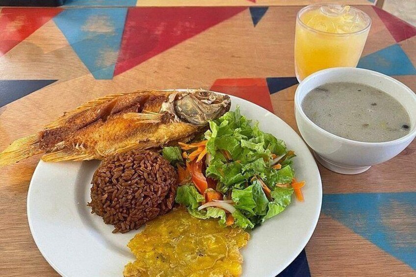 A plate with fried fish, rice, salad, and a bowl of soup. 4