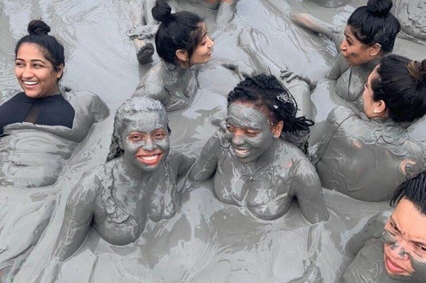 Mensen bedekt met een grijze substantie, waarschijnlijk modder, in het water. 2