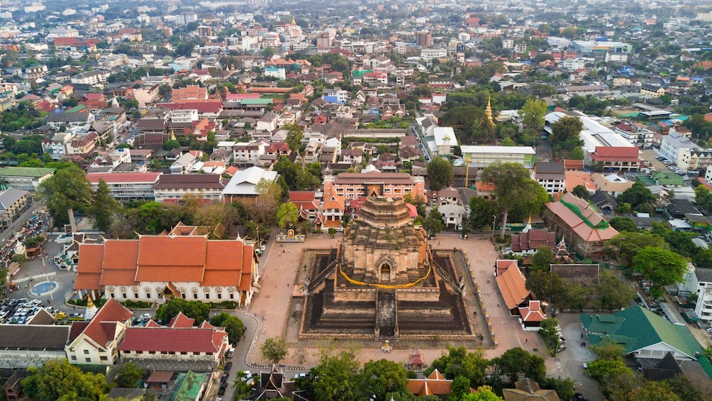An aerial view of a city with a prominent temple complex in the center, surrounded by residential and commercial buildings. 2