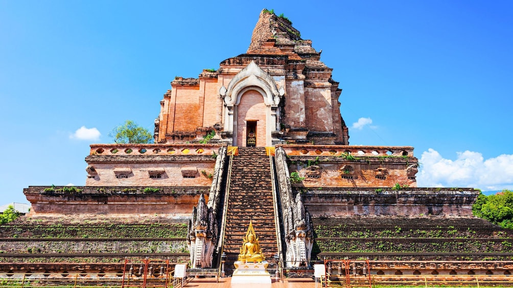 A temple with a golden statue at the entrance, surrounded by steps and bell towers. 5