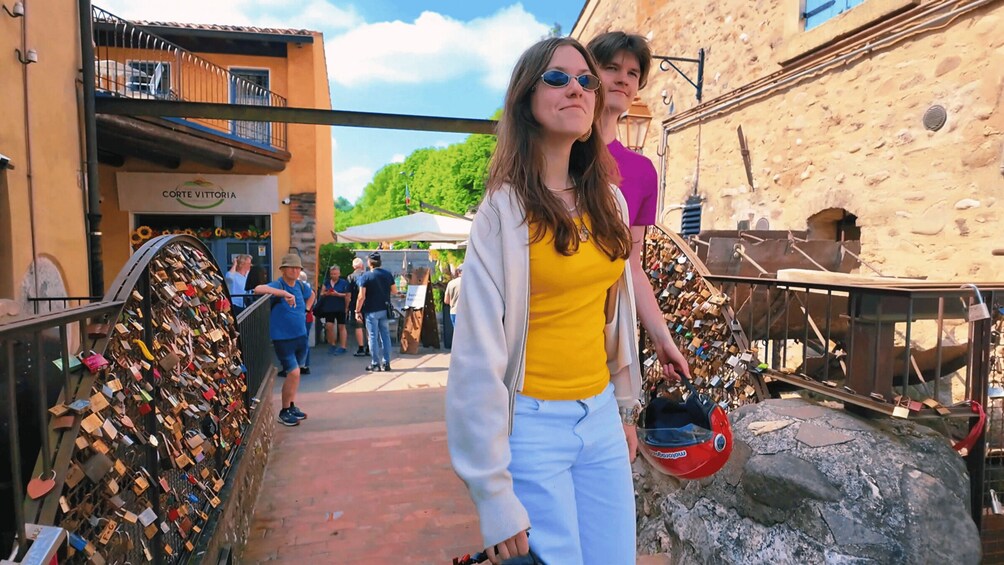 A person holding a helmet, walking past a wall of padlocks. 2