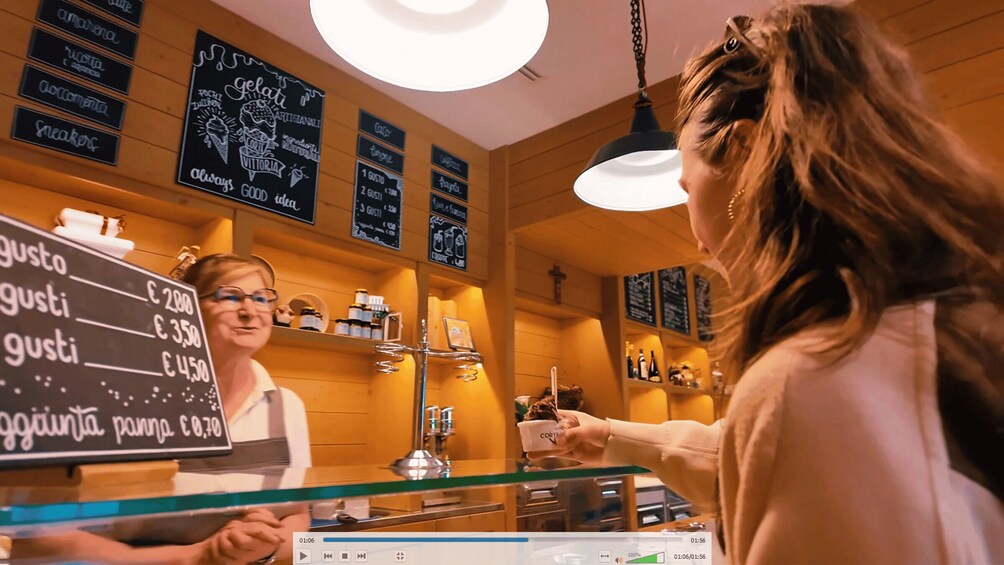 A person at a counter in a cafe with a menu board displaying prices. 5