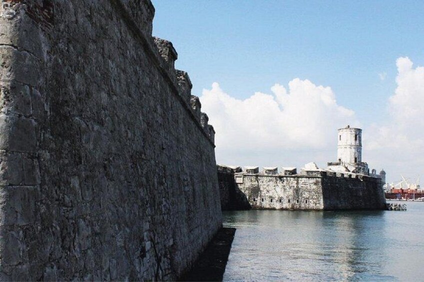 Un muro di pietra e una torre accanto a un'acqua tranquilla. 1