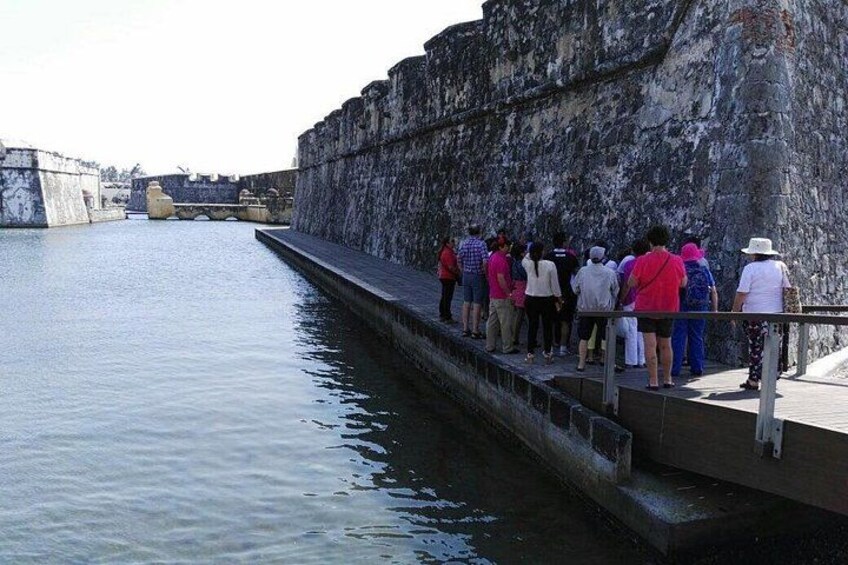 Un gruppo di persone in piedi su un muro di pietra, con vista su un corso d'acqua e un ponte. 3