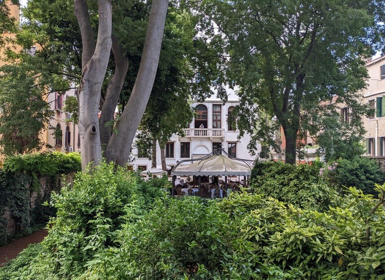 A white building with a balcony, surrounded by lush greenery and trees. 3