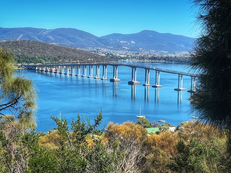Un puente largo sobre un río tranquilo, con montañas al fondo. 4