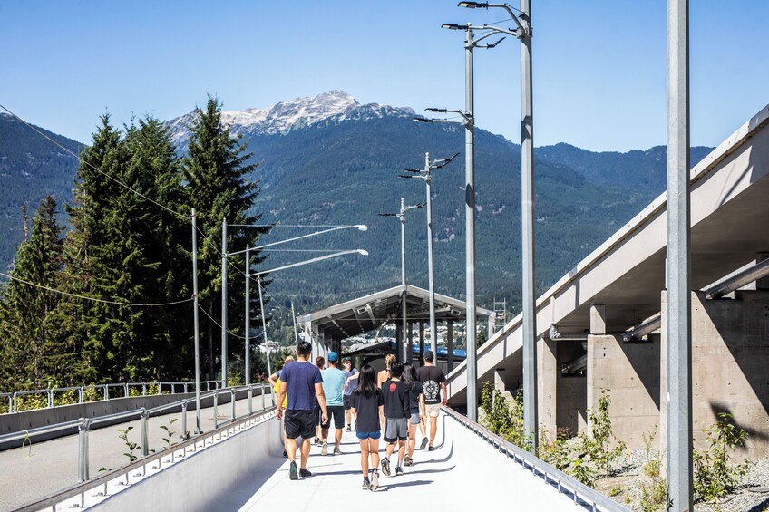Un grupo de personas caminando sobre un puente con una montaña de fondo. 2