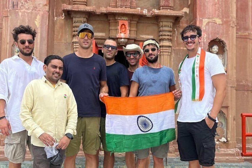 A group of people holding an Indian flag in front of a historic building. 3