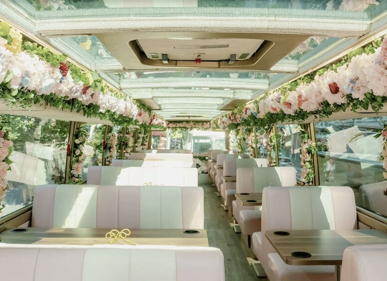 A train carriage with white seats and tables, adorned with floral decorations and greenery. 2