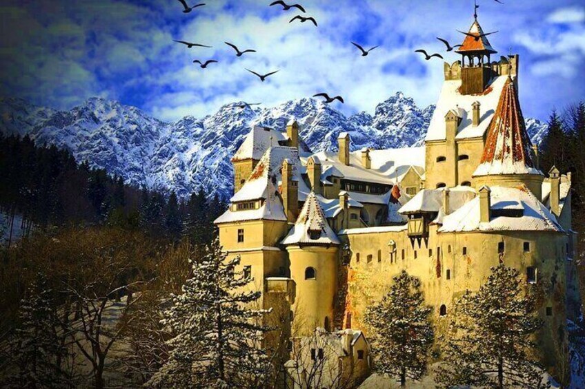 A castle with snow-covered roofs and a mountainous backdrop. 1