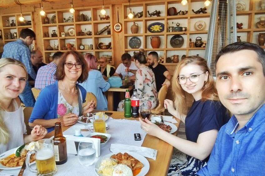 A restaurant with wooden shelves filled with pottery and dishes. People are dining at tables with food and drinks. 3