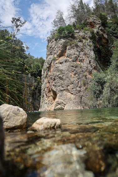 A rocky cliff with a river in the foreground. 3