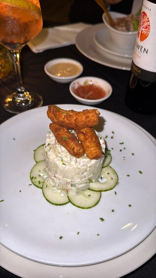 A plated dish with a creamy base, cucumber slices, and fried items on top. 5