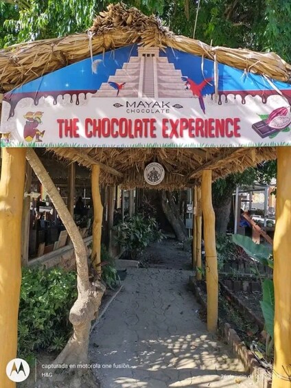 A Mayak Chocolate Experience pavilion with a thatched roof and a signboard. 5