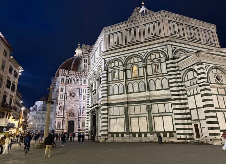 A nighttime view of the Florence Cathedral with tourists walking in the square. 2