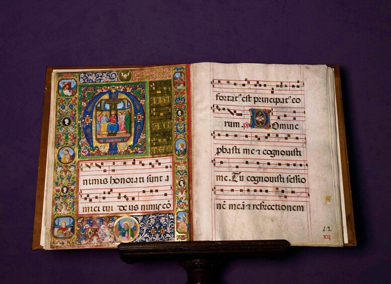 An open, ornate medieval manuscript with colorful illustrations and text. 5