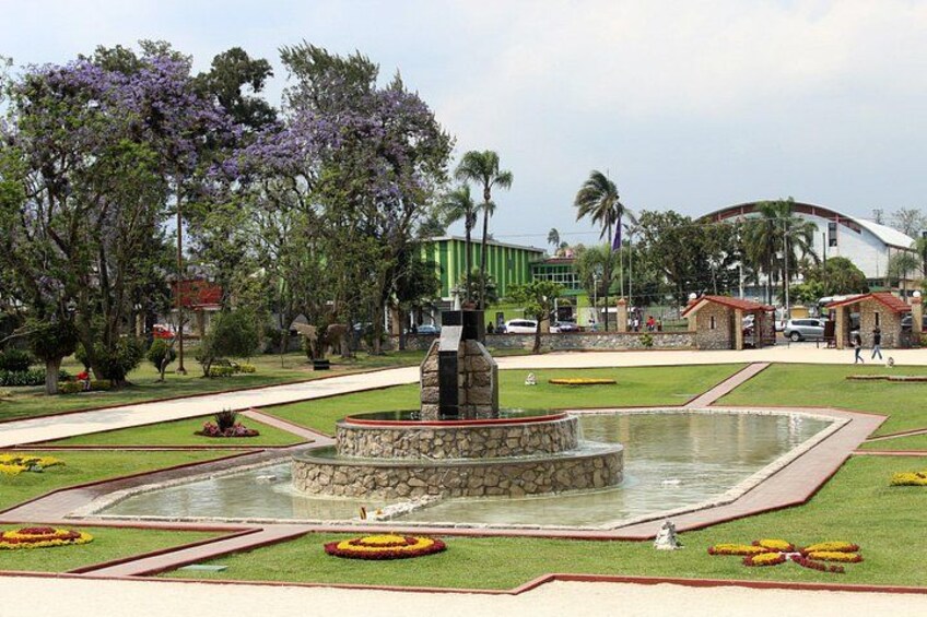 A landscaped garden with a central fountain, surrounded by manicured lawns and flower beds. 2