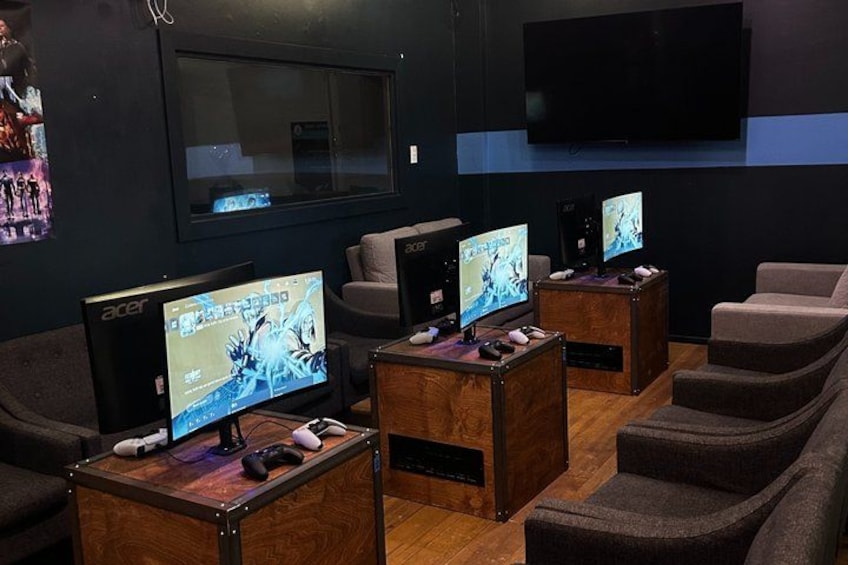 A gaming lounge with multiple gaming stations, each with a monitor, keyboard, and mouse. 2