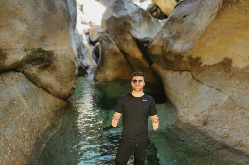 Une personne se tient debout dans un étroit canal d’eau, entre de gros rochers. 5